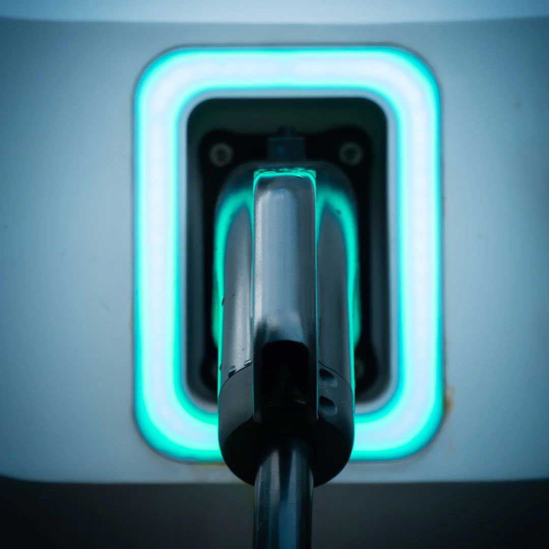 Close-up of a home EV charging socket with cable plugged in and glowing blue LED ring, installed in Gloucestershire.