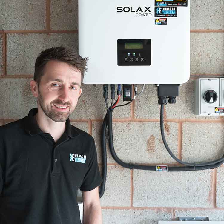 A satisified Hands On Electrical engineer smiles alongside another successful solar PV backup battery installation